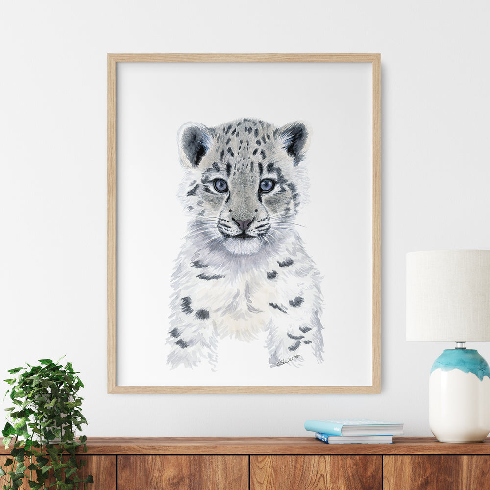 a framed picture of a snow leopard cub