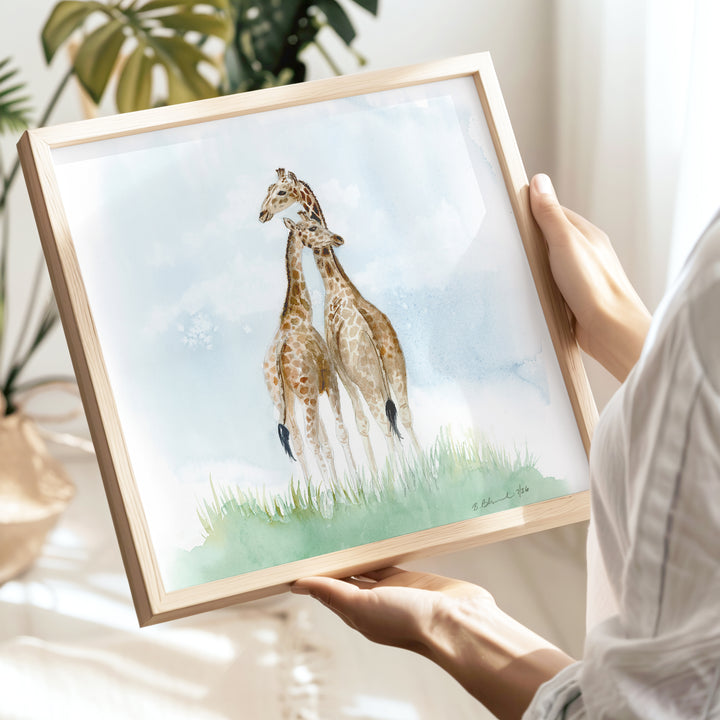 framed mom and baby giraffe nursery print held by an expecting mom