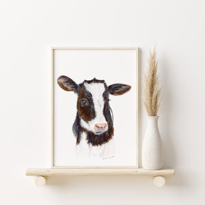 a picture of a cow on a shelf next to a vase