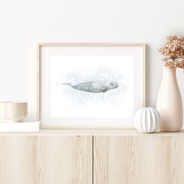 a picture of a beluga whale on a shelf next to a vase with flowers